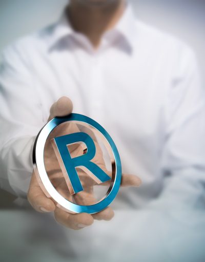 Man holding metallic registered trademark symbol. Concept image for illustration of intellectual property or protection of products or services.